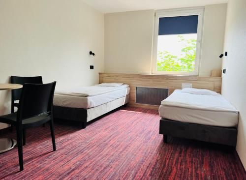 a room with two beds and a table and a window at Hotel ROK in Kraków