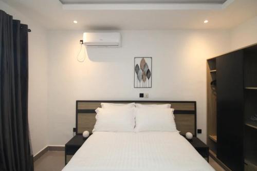 a bedroom with a large bed with white sheets at VOAK Home in Douala