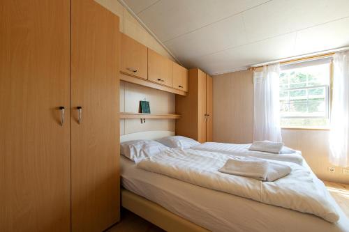 een slaapkamer met een groot bed en een raam bij 79, Ruime chalet aan de Kampina in Oisterwijk