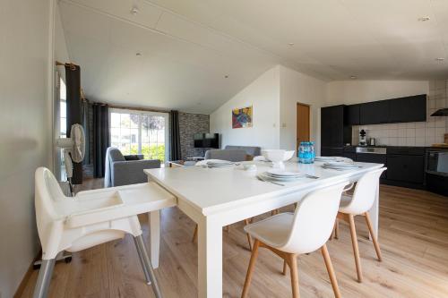 a kitchen and living room with a white table and chairs at 79, Ruime chalet aan de Kampina in Oisterwijk