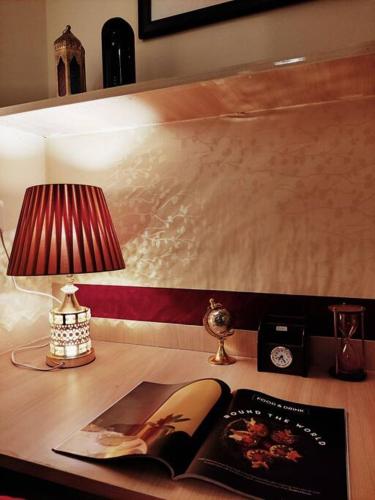 a table with a lamp and a book and a clock at Dubai Suite by Hey Studios in Ghaziabad