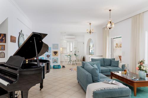 un soggiorno con pianoforte e divano blu di Naxos Beach Front Villa ''Moments'' ad Ambrami