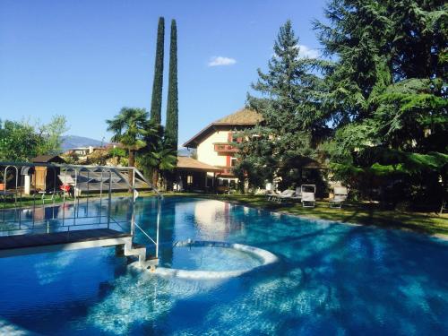 a large swimming pool with blue water and trees at Angerburg Blumenhotel in Appiano sulla Strada del Vino