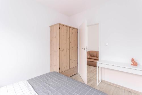 a bedroom with a bed and a wooden cabinet at Chill Apartments Bociania in Warsaw