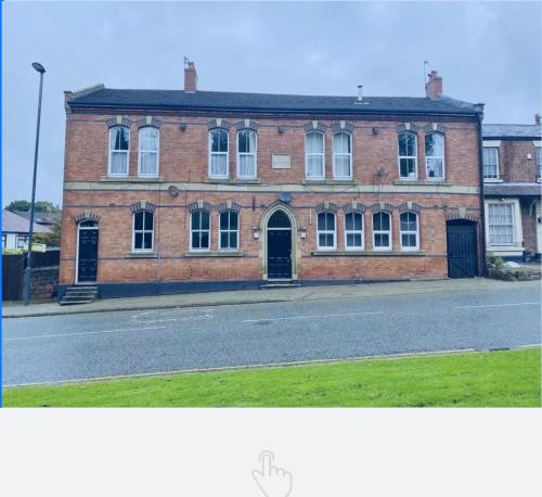 a large brick building with a door on a street at Shakespeare’s Nest in Prescot