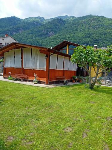 una casa con un césped verde delante de ella en L'Alpina Affittacamere, en Bobbio Pellice