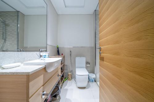La salle de bains est pourvue de toilettes, d'un lavabo et d'un miroir. dans l'établissement ALH Vacay - Brand New Studio in Azizi Aura Jebel Ali, à Dubaï