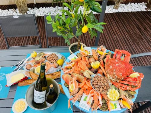 a table with a plate of seafood and a bottle of wine at Scorfel Lodge, Villa Matisse, Spa & terrasse in Perros-Guirec