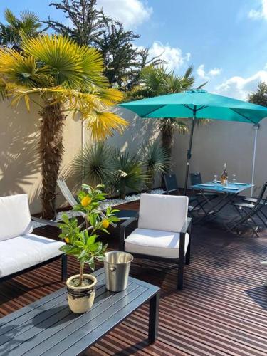 un patio avec deux chaises, une table et un parasol dans l'établissement Scorfel Lodge, Villa Matisse, Spa & terrasse, à Perros-Guirec