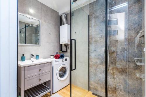 uma casa de banho com uma máquina de lavar roupa e um chuveiro em Serene Apartment in the City Center em Cracóvia