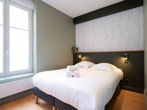 une chambre avec un grand lit blanc avec deux serviettes dessus dans l'établissement La cachette de Stanislas, à Nancy