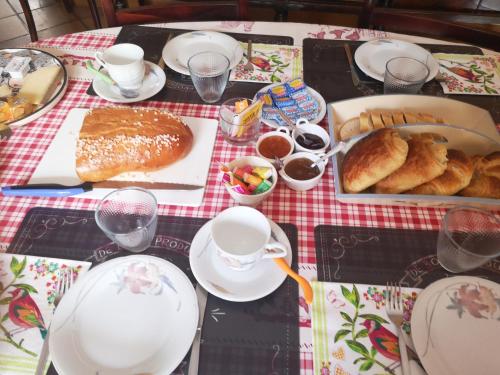 a table with bread and cups and plates of food at Chez Eliane in Villeneuve-la-Comptal