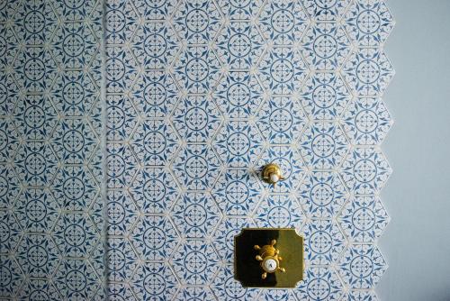 a bathroom with a blue and white tile wall with a switch at Le Petit Chateau & William de Percy in Otterburn