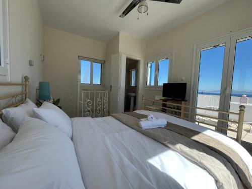 Schlafzimmer mit einem großen weißen Bett und einem Balkon in der Unterkunft Amalia's Summer Home in Áyioi Asómatoi