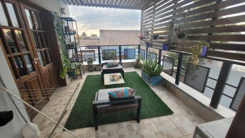 balcón con sofá y mesa sobre alfombra en departamento confortable en Luján de Cuyo