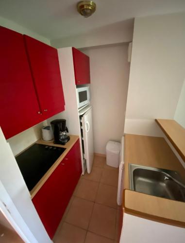 a small kitchen with red cabinets and a sink at Lac Mondésir the little house and its Bastide in Monflanquin