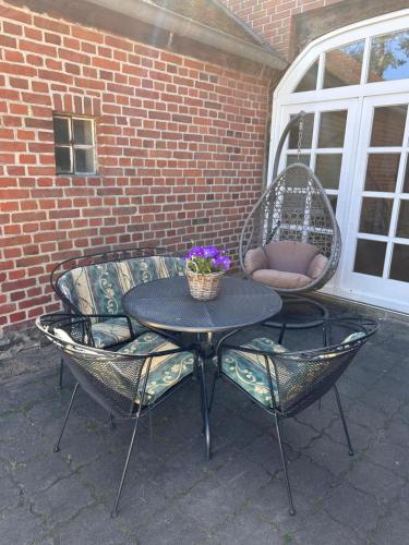 d'une terrasse avec une table, des chaises et une chaise en osier. dans l'établissement Hof Baden, Ferienwohnung, à Schneverdingen