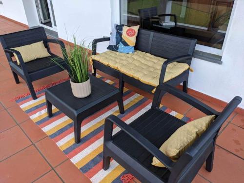 a porch with three chairs and a bench and a table at casa panorâmica bela vista in Angra do Heroísmo