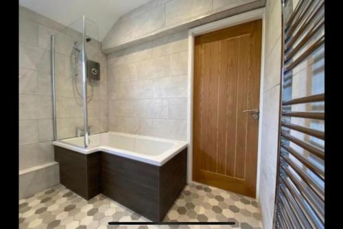 a bathroom with a bath tub and a shower at Lake District Coastal cottage in Seascale