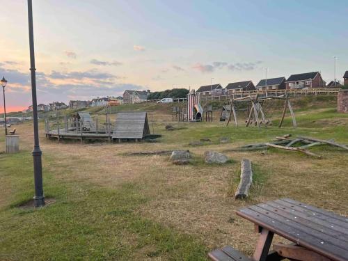 a park with a playground with a bench at Lake District Coastal cottage in Seascale