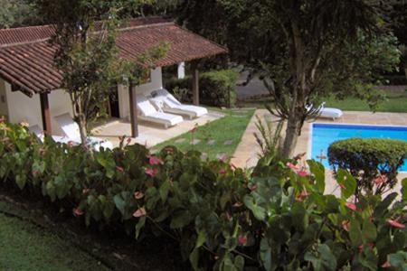 a garden with a swimming pool and some plants at Canto do Bosque - Chalé Sabiá com hidromassagem in Araras Petropolis