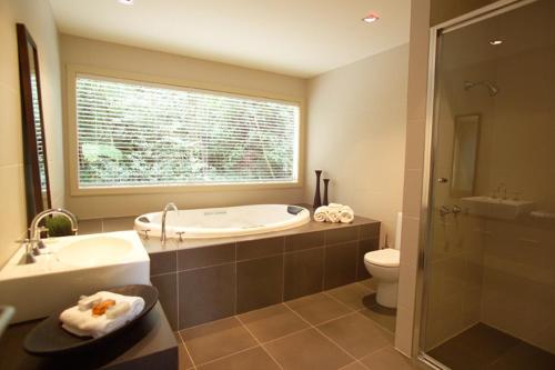 a bathroom with a tub and a toilet and a window at Lochiel Luxury Accommodation in Olinda