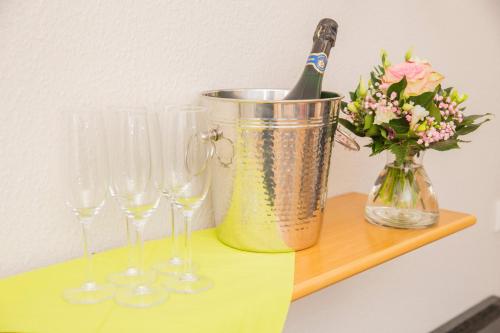 a bucket with wine glasses and a vase with flowers at Hotel-Pension Haus Holtdirk in Lippstadt