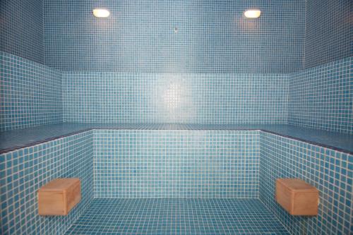 a blue tiled bathroom with a tub and two stools at Apartagal-Costa Reinante Spa in Barreiros