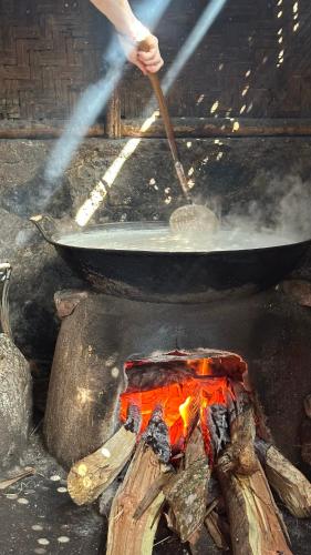 a person cooking food in a pan over a fire at Jonny's Places in Tetebatu