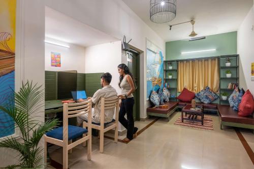 a man and a woman standing in a living room with a table at Zostel Kochi, Fort Kochi in Cochin
