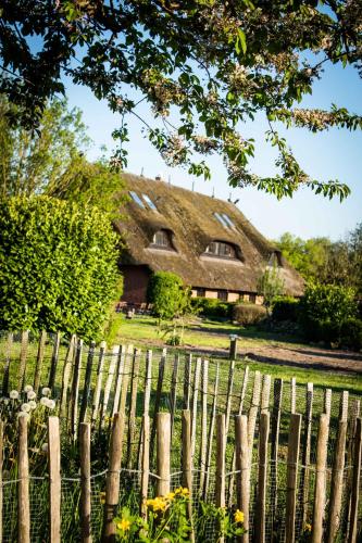 an old house with a thatched roof behind a fence at Gutshof Bastorf in Kühlungsborn