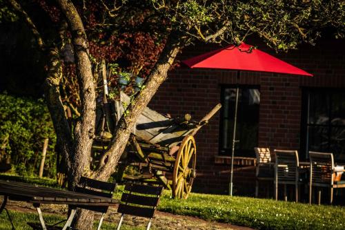 a red umbrella and a wooden cart in front of a house at Gutshof Bastorf in Kühlungsborn