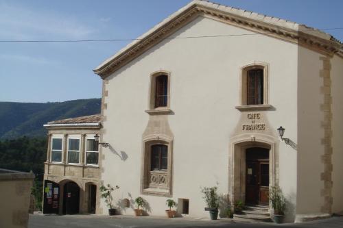 un bâtiment blanc avec un panneau à l'avant dans l'établissement Cafe de france, à Lacoste