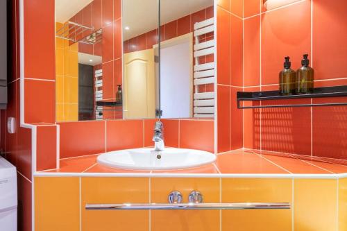 La salle de bains est pourvue de murs orange et d'un lavabo. dans l'établissement City Escape, au Bourget