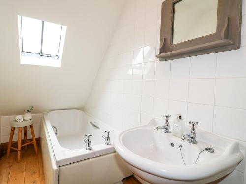 y baño blanco con lavabo y bañera. en Postbox Cottage en Ashbourne