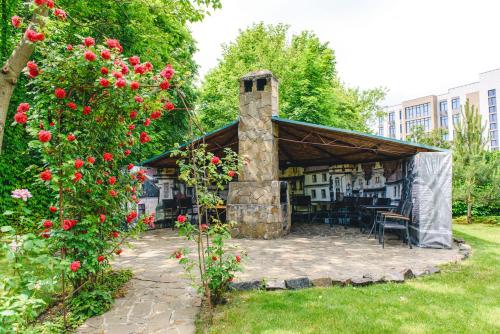 a building with a stone fireplace in a yard with roses at Sovinyon Resort in Odesa