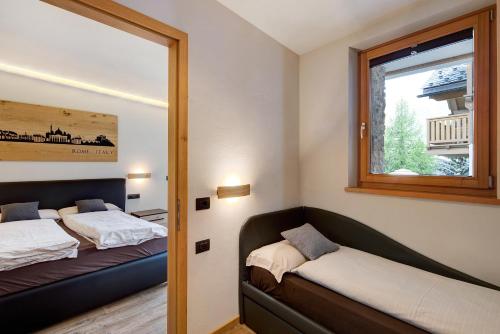 een slaapkamer met 2 bedden en een raam bij Chalet Monteneve Appartamento Neve in Livigno