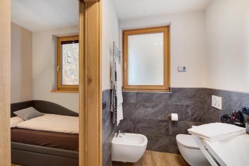 een badkamer met een wastafel, een toilet en een bed bij Chalet Monteneve Appartamento Neve in Livigno