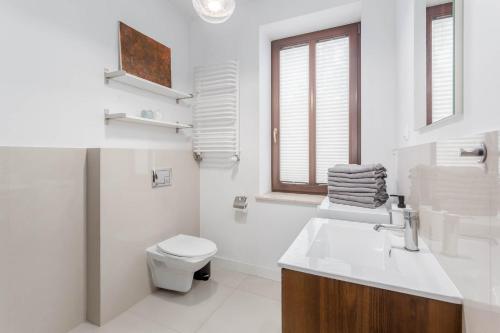 a white bathroom with a toilet and a sink at Chill Apartments Bociania in Warsaw