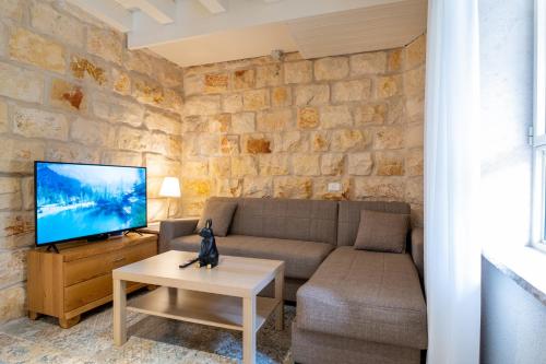 a living room with a couch and a tv at Via Maria Boutique Suites In The Middle Of The city in Haifa