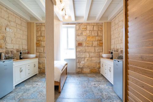 baño con 2 lavabos y pared de piedra en Via Maria Boutique Suites In The Middle Of The city en Haifa