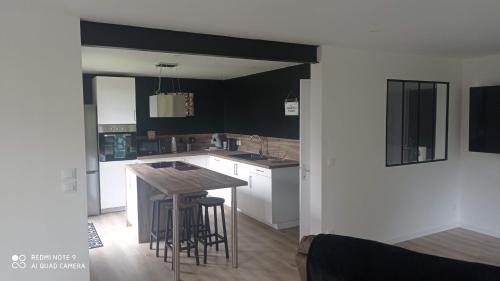 une cuisine avec des placards blancs, une table et des tabourets dans l'établissement LA BELLA 12-Appartement rez de chaussée 90m², à Bordeaux-Saint-Clair