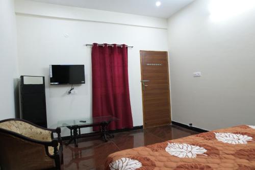a bedroom with a bed and a table and a tv at Forest View Resort in Yercaud