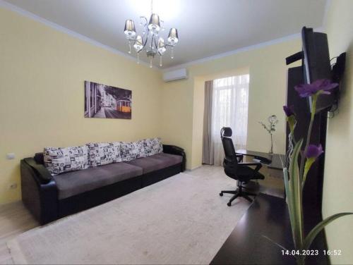 a living room with a black couch and a desk at Стильный уют в центре in Almaty