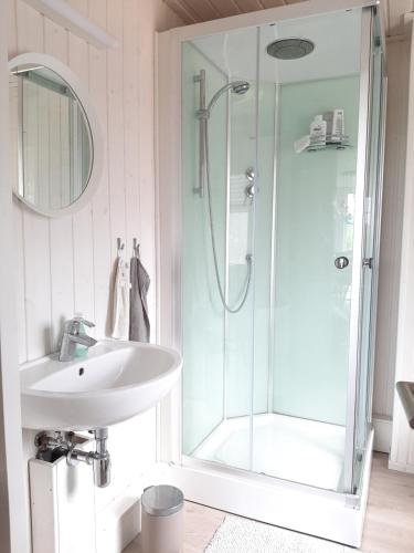 een witte badkamer met een douche en een wastafel bij Annemarie Zerpenschleuse - Schwedenhaus mit Künstler-Charme und Sauna in Zerpenschleuse