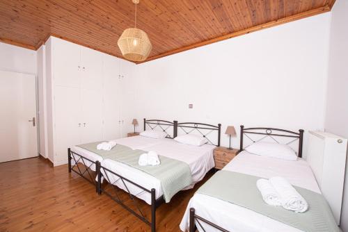 two beds in a room with white walls and wooden floors at Perispit in Lefkada