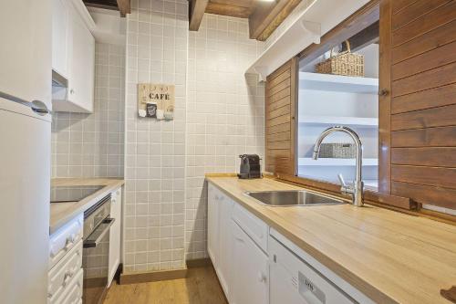 a kitchen with white cabinets and a sink and a window at Luderna - Casa Catania in Naut Aran