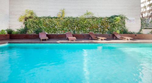 a swimming pool with chairs next to a building at Ilunion Valencia 4 in Valencia