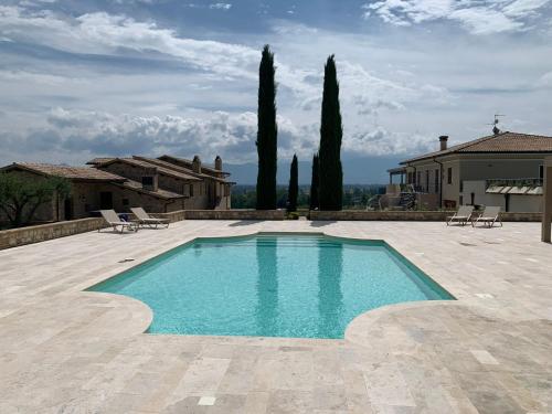a swimming pool in front of a house with trees at Fattoria Colsanto in Torre del Colle