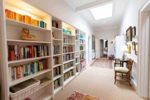 a library with white shelves filled with books at The West Wing - Bride Valley - Jurassic Coast in Long Bredy